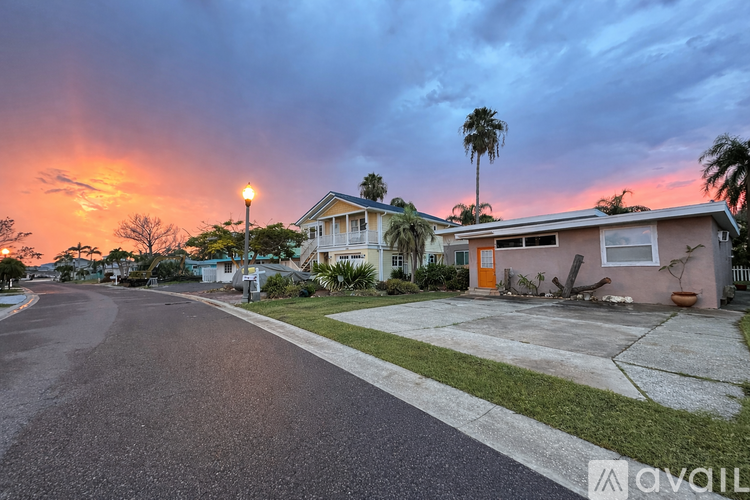 A street view of a residential area with houses and palm trees.
