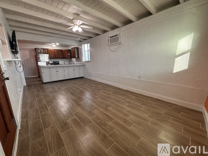 A spacious room with wooden flooring and a ceiling fan.