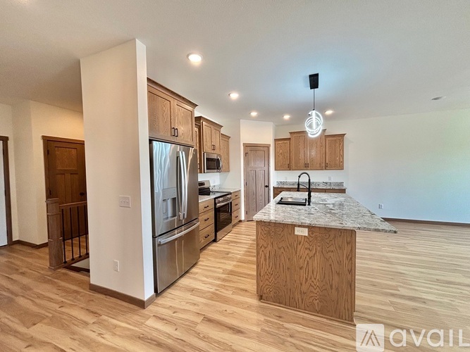 A kitchen with wooden cabinets and a marble island.