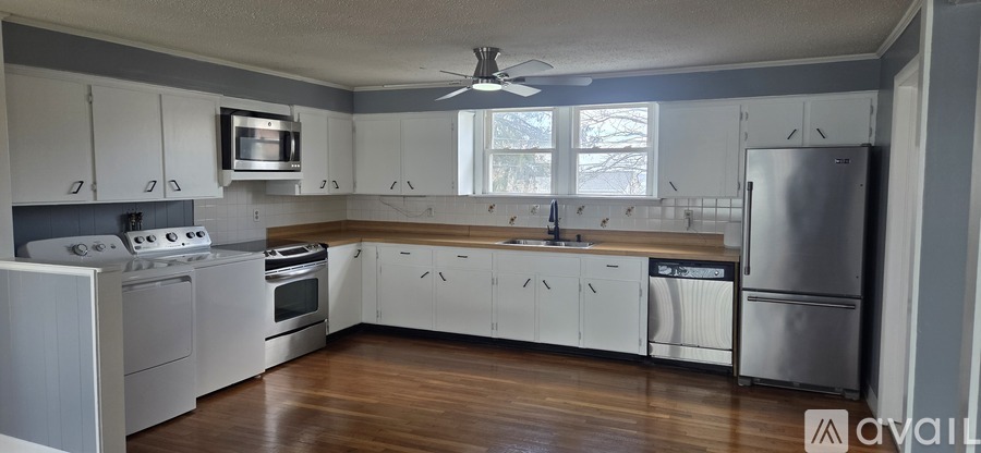 A kitchen with white cabinets and a wooden floor.