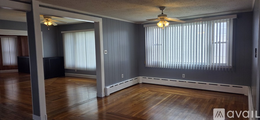 A spacious living room with wood floors and a ceiling fan.