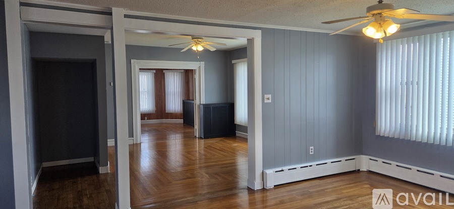 A room with a ceiling fan and wooden floors.