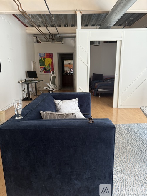 A blue couch with a white pillow and a glass of water on it.
