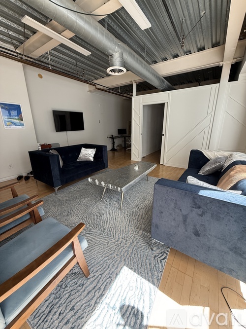 A living room with a grey rug and a blue couch.