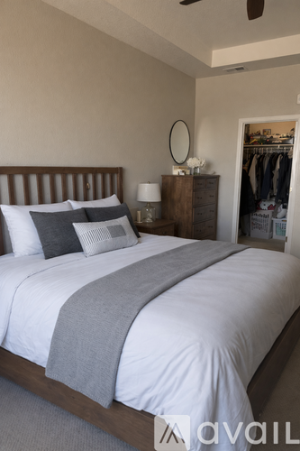 A bedroom with a large bed and a clothing rack in the background.