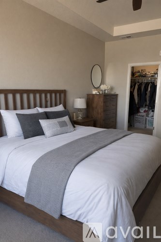 A bedroom with a large bed and a clothing rack in the background.