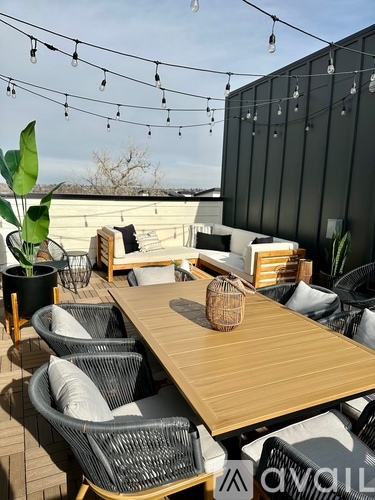 A wooden table with wicker chairs and a potted plant on a patio.