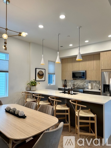A modern kitchen with wooden furniture and pendant lights.