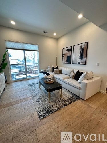 A living room with a white couch and a coffee table in front of a large window.
