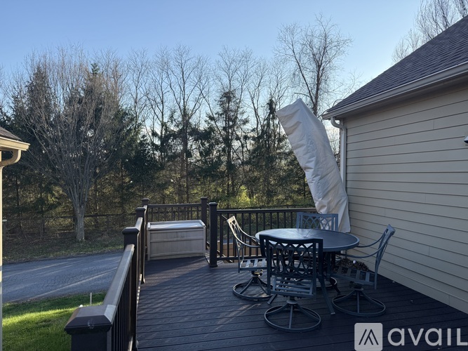 A deck with a table and chairs is surrounded by trees.