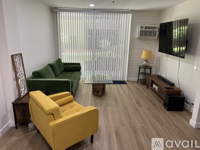 A living room with a yellow chair, green couch, and a television.