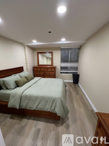 A bedroom with a bed, nightstand, and window.