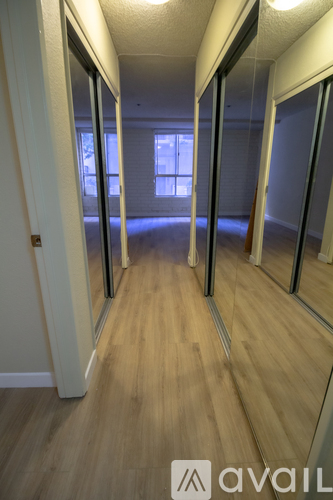 A hallway with wooden floors and mirrors on the wall.