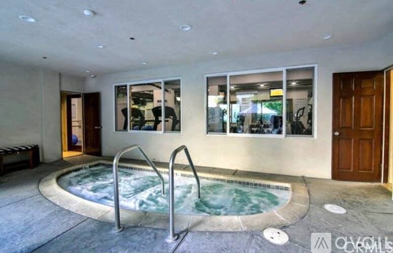 A hot tub is in the middle of a room with a glass wall.
