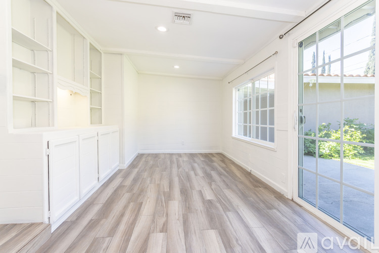 A spacious room with wooden flooring and white walls.