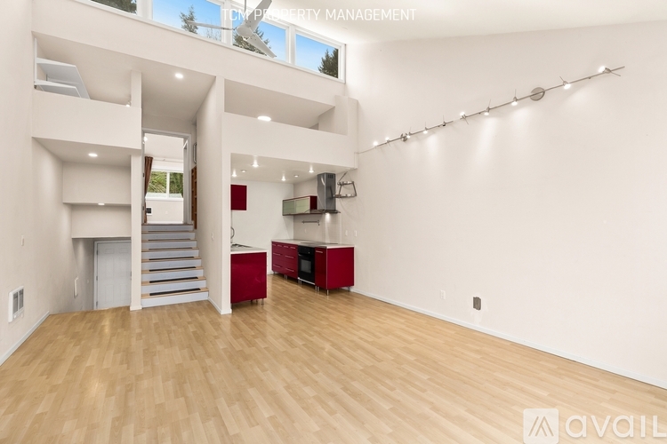 A spacious room with wooden flooring and a staircase leading to another level.