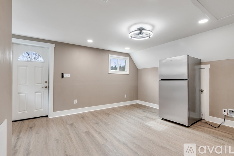 A kitchen area with a refrigerator, wooden flooring, and a window.