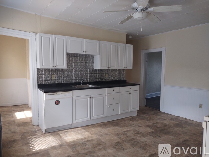 A kitchen with white cabinets and a black countertop.
