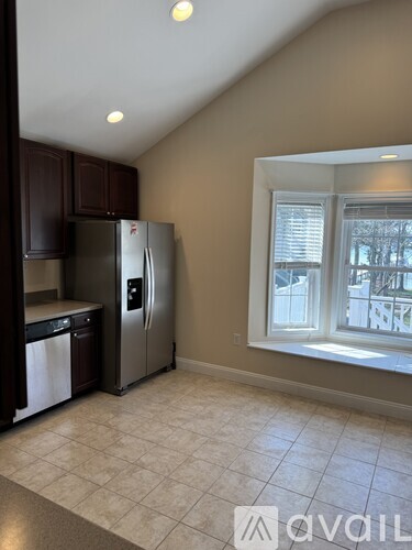 A kitchen with a refrigerator, dishwasher, and a window.