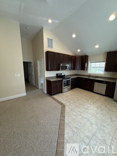 A spacious kitchen with dark brown cabinets and a tiled floor.