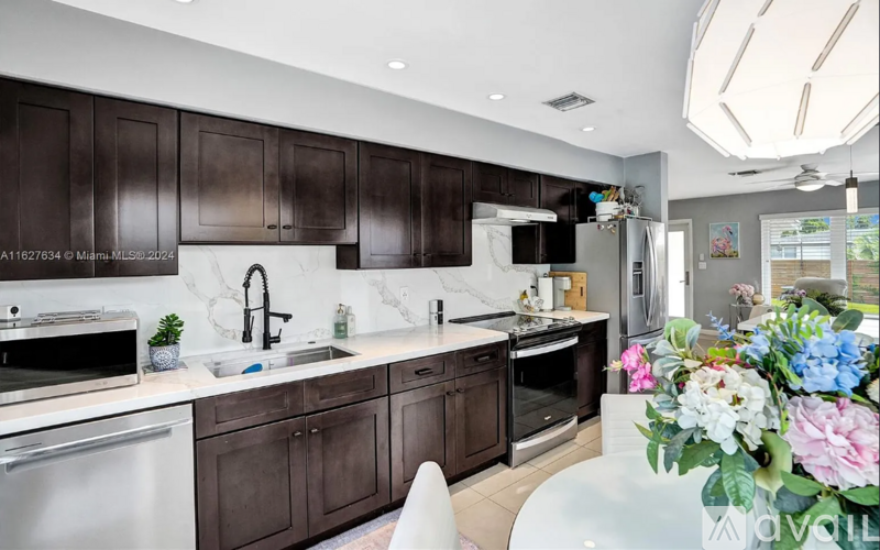 A kitchen with dark brown cabinets and white countertops.