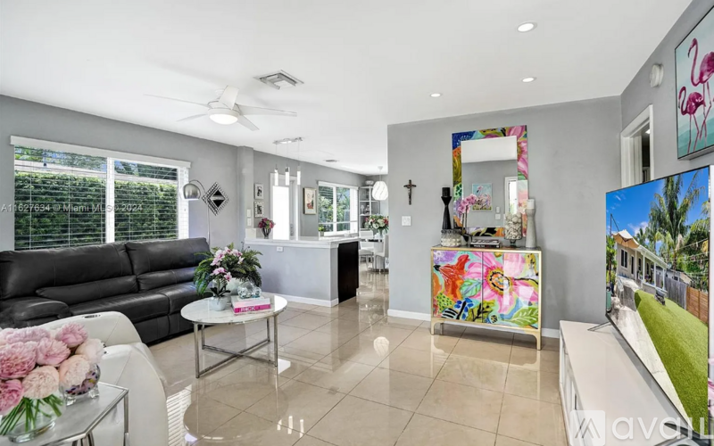 A living room with a black couch, a white coffee table, and a painting on the wall.