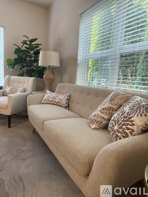 A beige couch with a lamp and a plant on a table.
