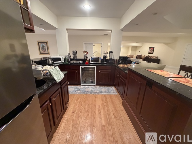 A kitchen with wooden floors and a refrigerator on the left.