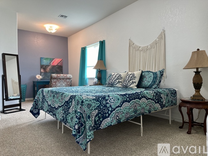 A bedroom with a bed covered in a blue and white patterned bedspread.
