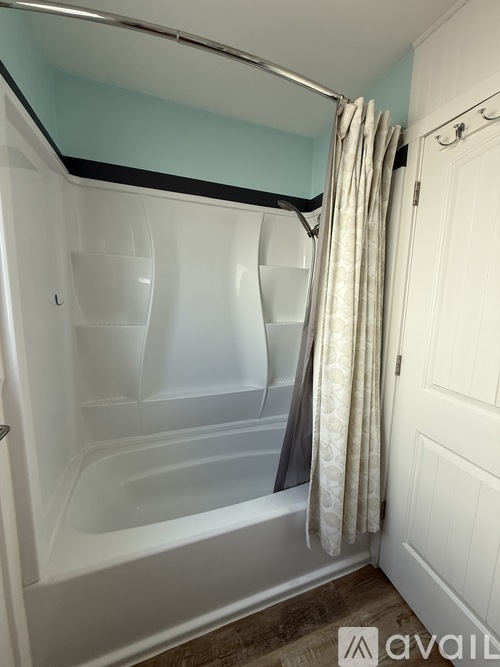 A bathroom with a white tub and a grey shower curtain.