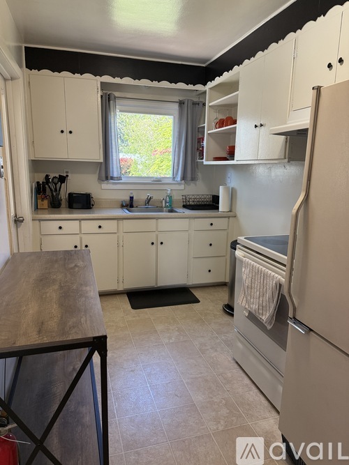 A kitchen with white cabinets and a refrigerator.