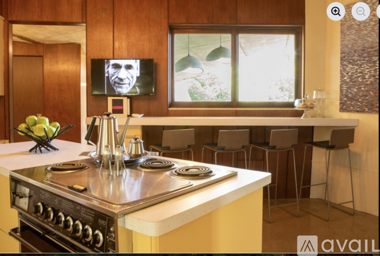 A modern kitchen with a stove top oven and a television mounted above the counter.