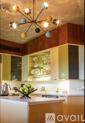 A kitchen with a white counter top and a chandelier with multiple lights.