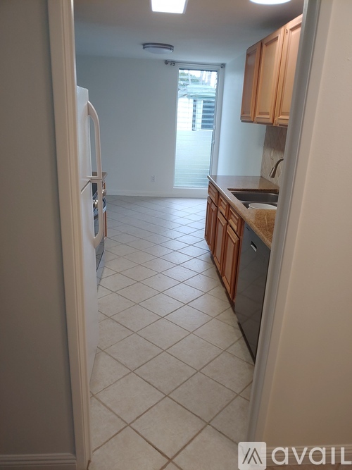A kitchen with a refrigerator, sink, and cabinets.