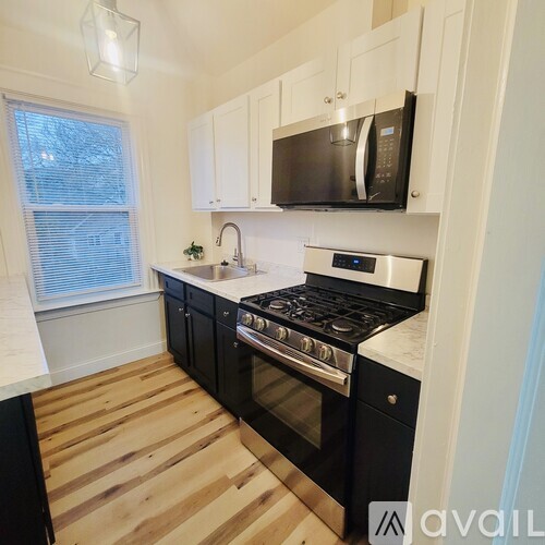 A kitchen with black cabinets and a black microwave above the stove.