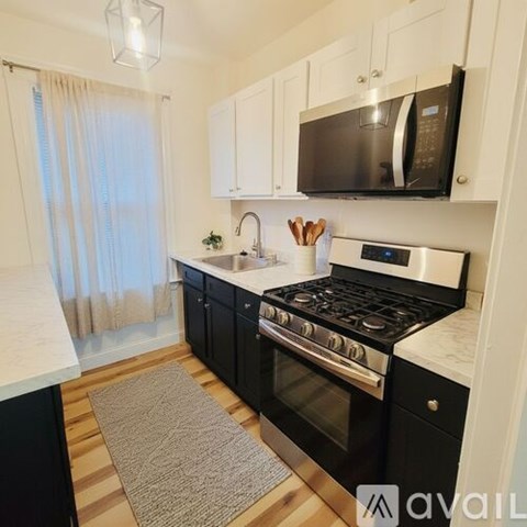 A kitchen with black cabinets and a black microwave above the stove.