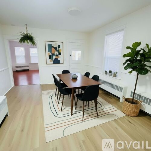 A living room with a grey couch, a black chair, a wooden floor and a flat screen TV mounted on the wall.