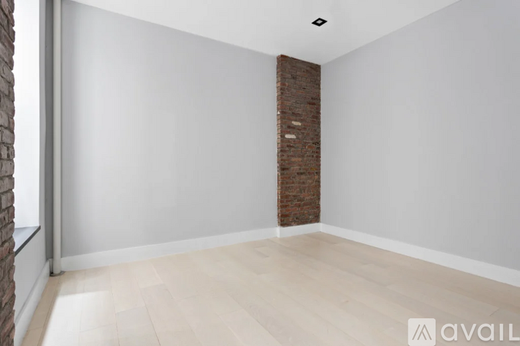 A room with a brick pillar and wooden flooring.
