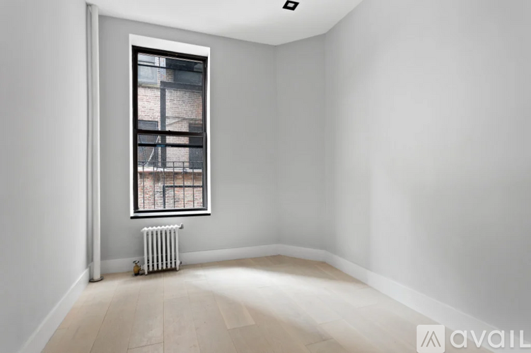 A room with a window and a radiator on the floor.