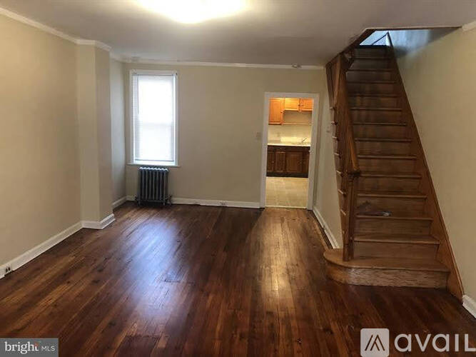 A room with wooden floors and a staircase leading to another room.