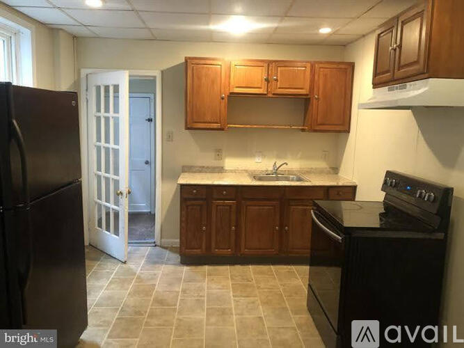 A kitchen with a black refrigerator, black stove, and wooden cabinets.