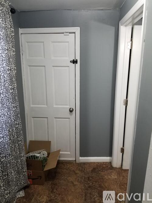 A white door is in a room with a cardboard box on the floor.
