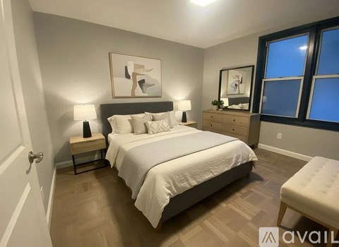 A bedroom with a large bed, a nightstand with a lamp, and a painting on the wall.