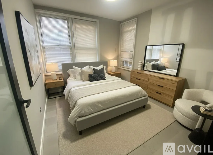 A bedroom with a large bed, a chair, and a dresser with a mirror.