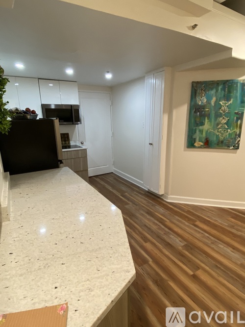 A kitchen with a white counter top and wooden floors.