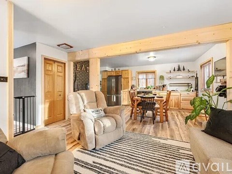 A living room with a striped rug and a dining area in the background.