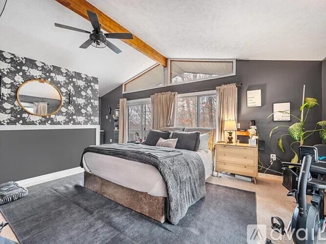 A bedroom with a large bed, a ceiling fan, and a mirror on the wall.