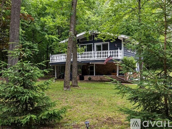 A house with a balcony is surrounded by trees.