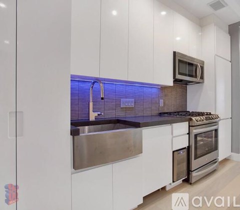 A modern kitchen with white cabinets and stainless steel appliances.