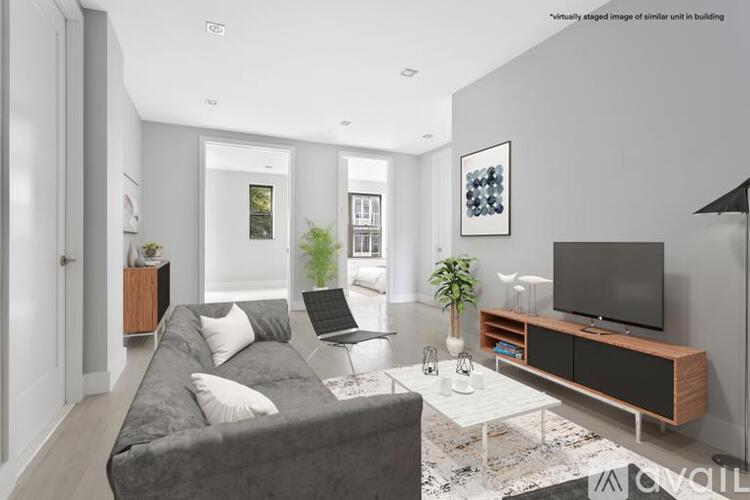 A modern living room with a grey couch, a white coffee table, and a flat screen TV.